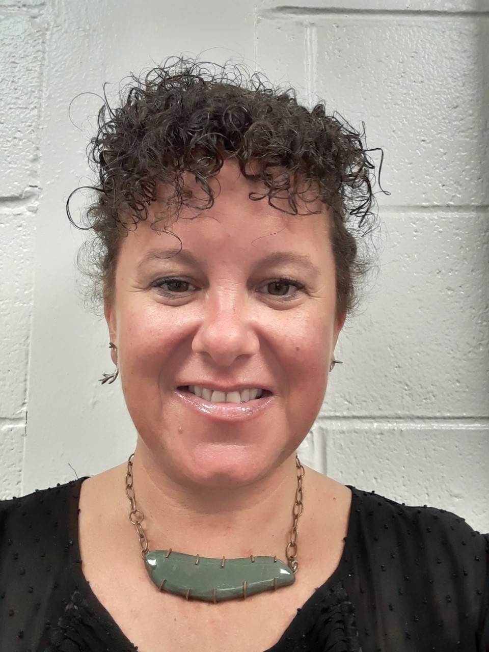 Susan standing in front of a brick wall seen from the shoulders up